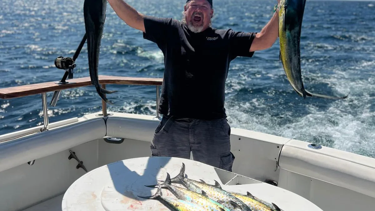 Un pescador con dos dorados en la bañera, el pescado que terminó en la parrilla del barco